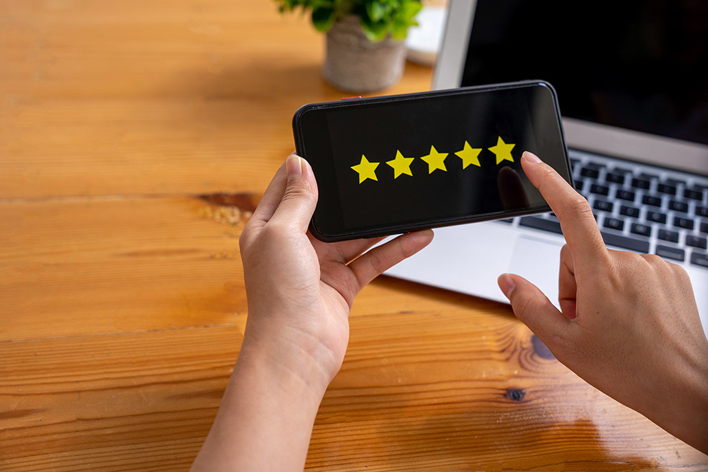 A person holding up a phone with five stars on it.