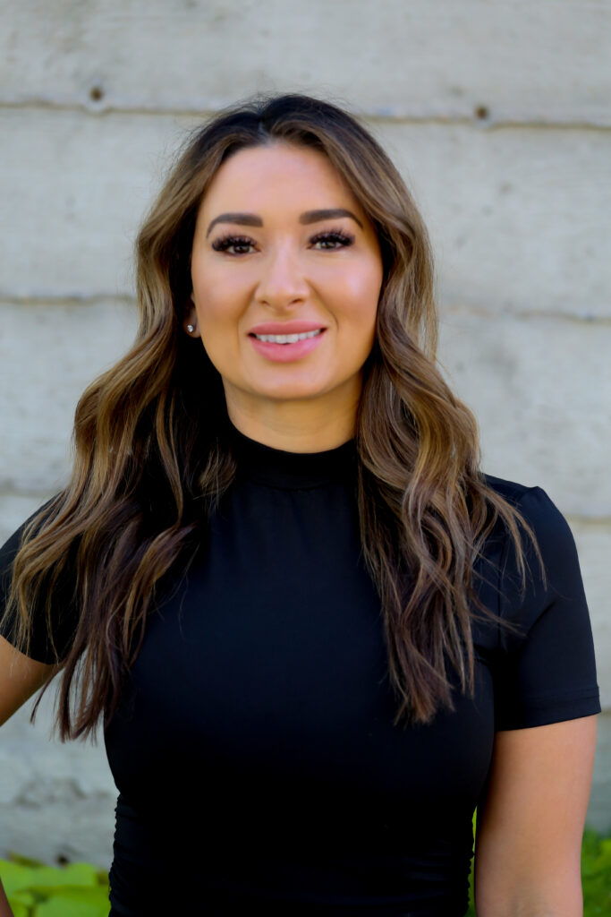 Woman smiling against a concrete wall background.